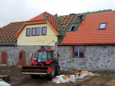 Darbinieki veic dakstiņa jumta uzstādīšanas darbus
