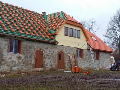 Darbinieki veic dakstiņa jumta uzstādīšanas darbus